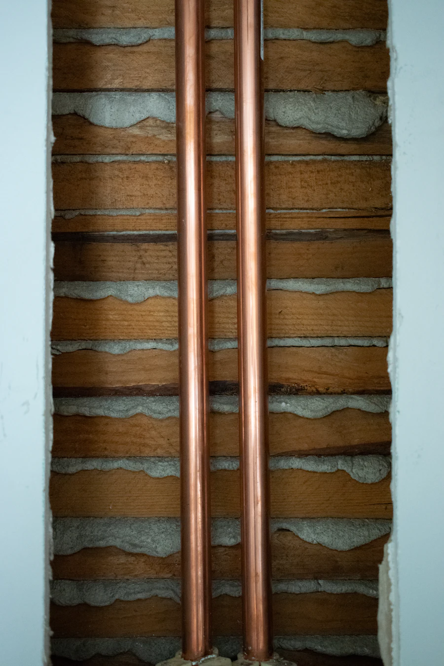Two new copper pipes running up a wall where the plaster has been opened up
